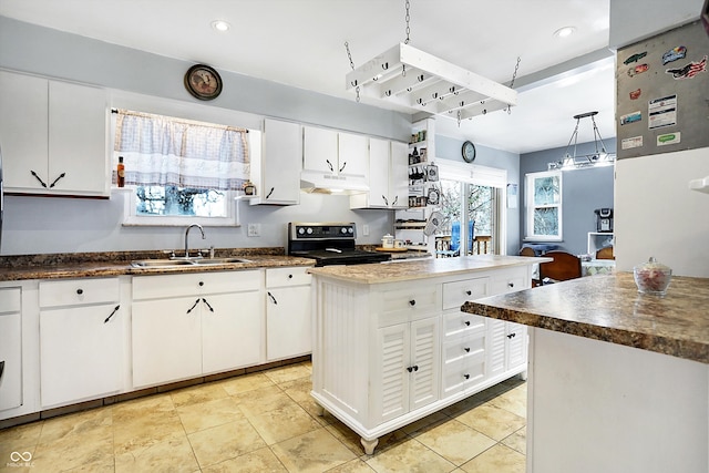 kitchen with a kitchen island, electric range oven, sink, white cabinets, and hanging light fixtures