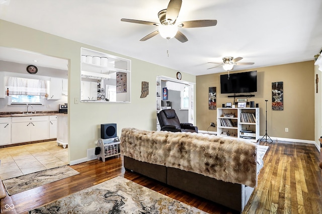 living room featuring hardwood / wood-style flooring, sink, and ceiling fan