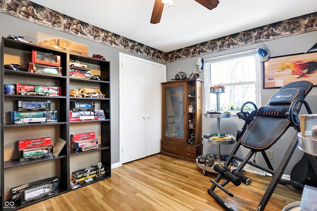 workout area featuring ceiling fan and light wood-type flooring