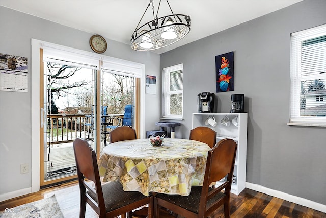 dining space with a healthy amount of sunlight, dark wood-type flooring, and a notable chandelier