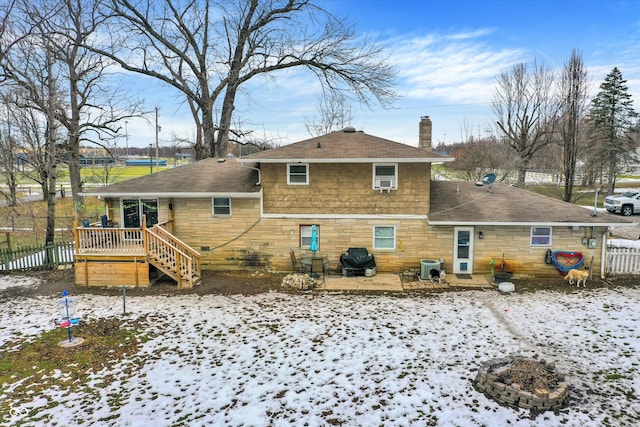 snow covered property with a wooden deck, an outdoor fire pit, and central air condition unit