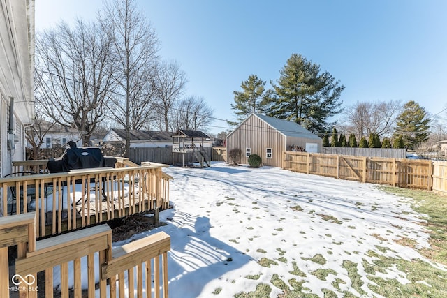 yard covered in snow with a wooden deck and a shed