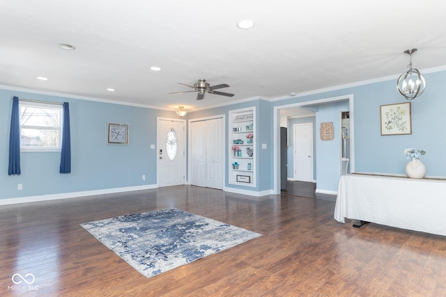 entrance foyer with crown molding, ceiling fan with notable chandelier, and dark hardwood / wood-style floors