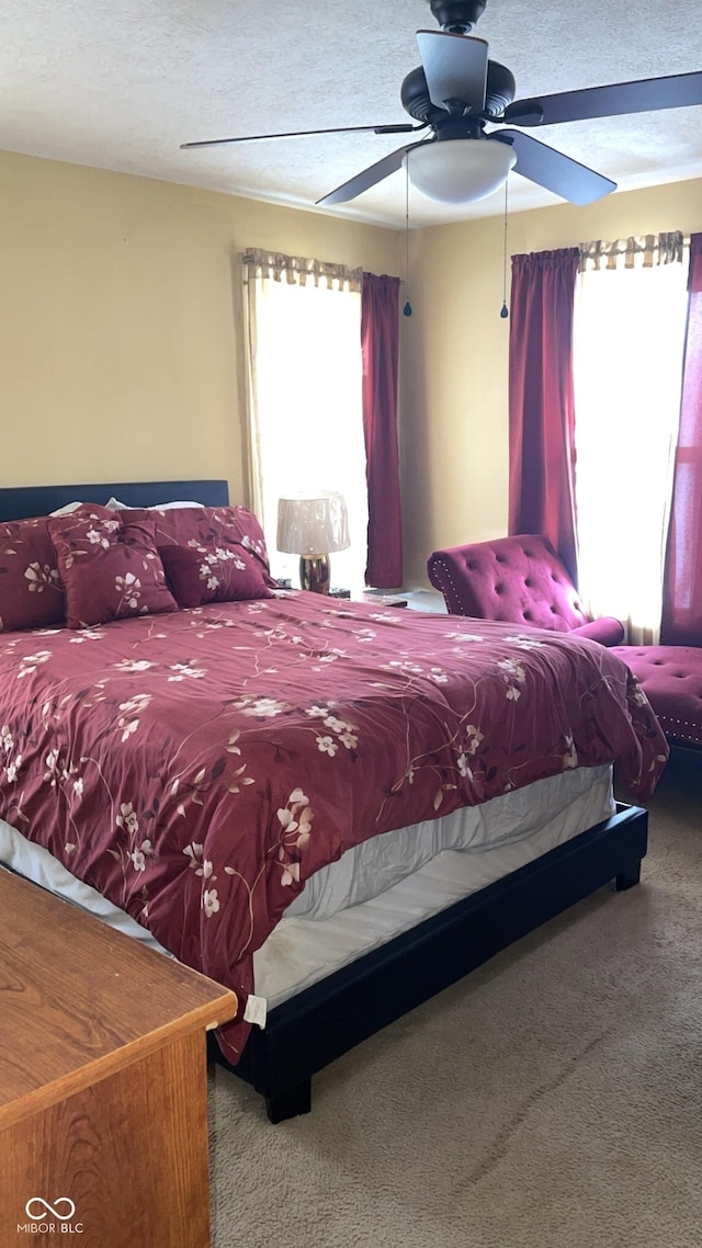 bedroom with ceiling fan, carpet, and a textured ceiling