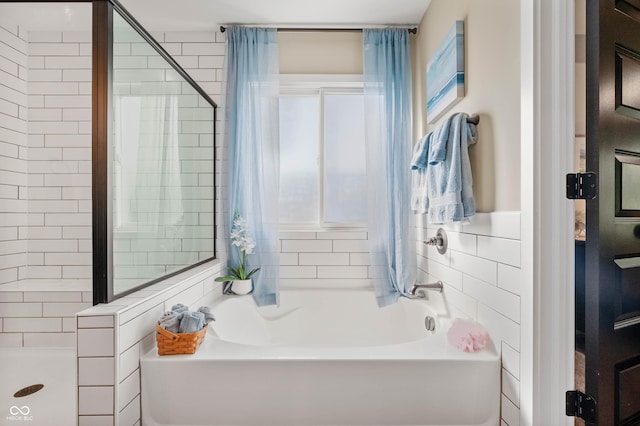 bathroom featuring shower with separate bathtub and tile walls