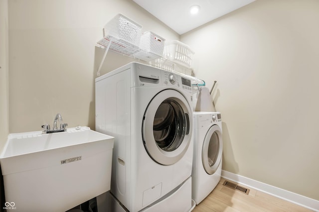 washroom featuring separate washer and dryer, sink, and light hardwood / wood-style flooring