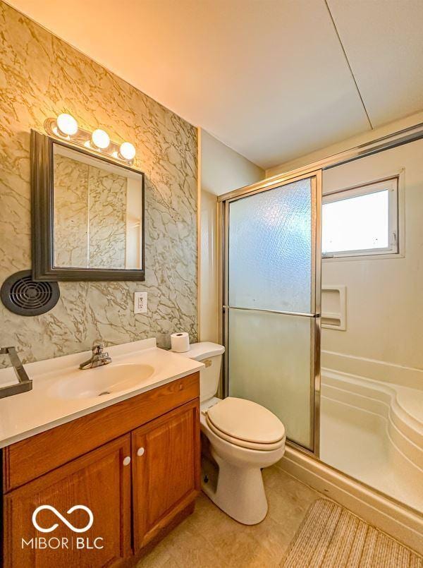 bathroom with tile patterned floors, vanity, toilet, and a shower with shower door