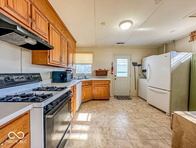 kitchen with sink, dishwasher, range with gas stovetop, washer / clothes dryer, and white fridge