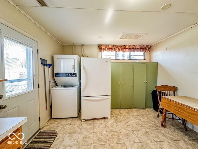 laundry area featuring ornamental molding, stacked washer and clothes dryer, and light tile patterned floors