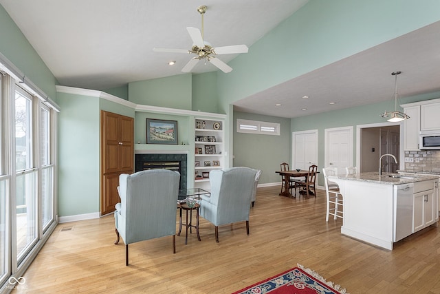 living room with sink, a fireplace, light hardwood / wood-style floors, and plenty of natural light