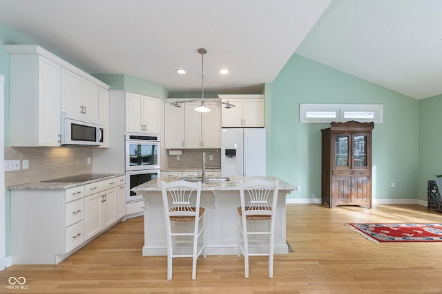 kitchen with sink, white cabinetry, hanging light fixtures, a center island with sink, and white appliances