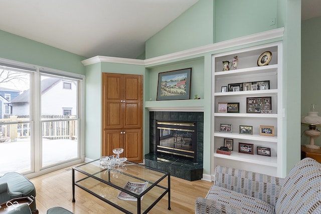 living room with plenty of natural light, lofted ceiling, a fireplace, and light hardwood / wood-style flooring