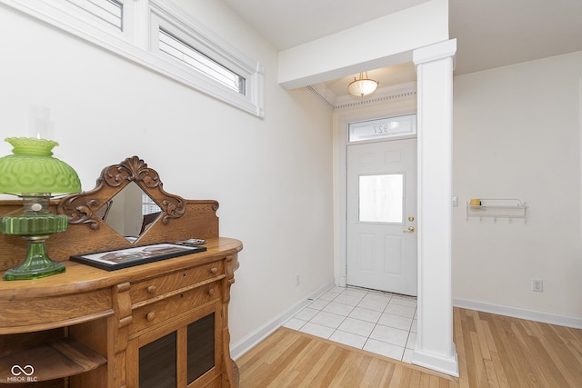 entryway featuring light hardwood / wood-style flooring, ornamental molding, and ornate columns