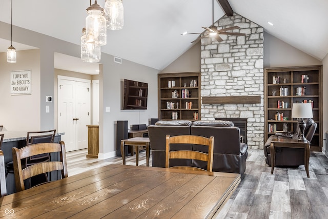 dining space with a fireplace, wood-type flooring, vaulted ceiling with beams, and ceiling fan