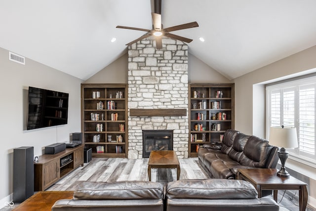 living room featuring vaulted ceiling, light wood-type flooring, ceiling fan, and a fireplace