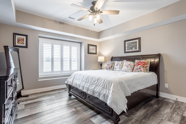 bedroom featuring a tray ceiling, wood-type flooring, and ceiling fan