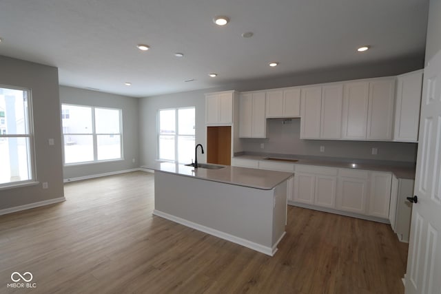 kitchen featuring sink, cooktop, an island with sink, and white cabinets