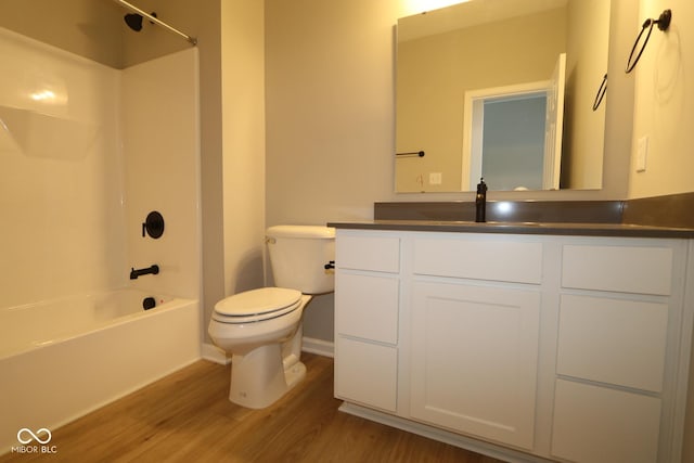 full bathroom with hardwood / wood-style flooring, vanity, washtub / shower combination, and toilet