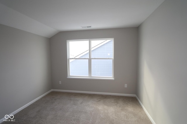 spare room featuring vaulted ceiling and carpet