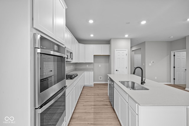 kitchen featuring a center island with sink, stainless steel appliances, white cabinetry, and sink