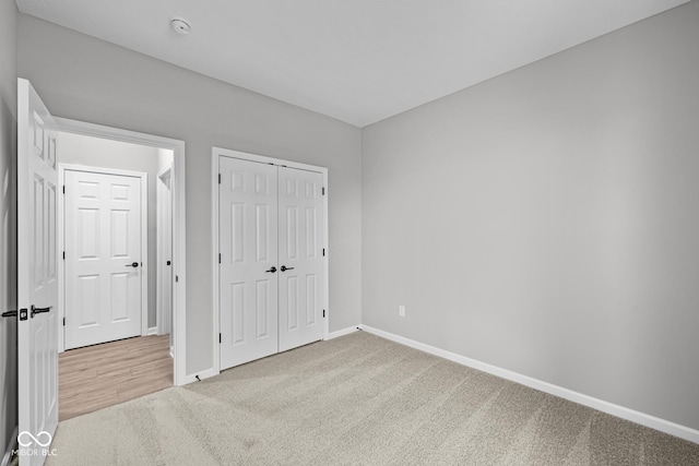 unfurnished bedroom with a closet and light colored carpet