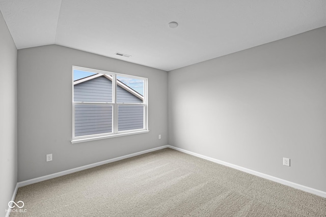 spare room featuring vaulted ceiling and carpet floors