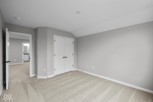 unfurnished bedroom with a closet, light colored carpet, and lofted ceiling