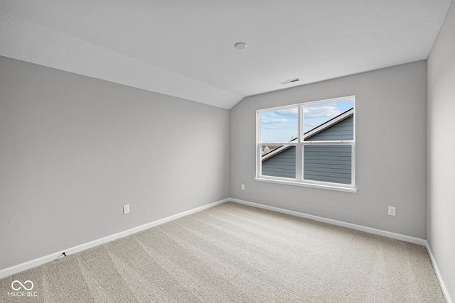 empty room featuring vaulted ceiling and carpet