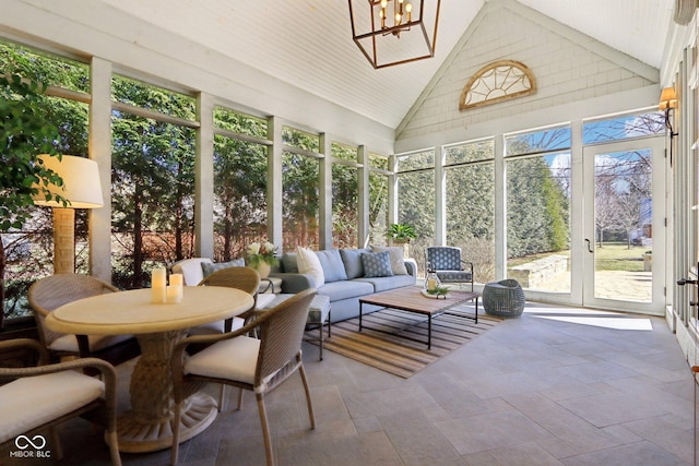 sunroom / solarium with a notable chandelier, a healthy amount of sunlight, and lofted ceiling