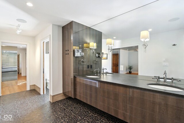 bathroom featuring a sink, baseboards, toilet, and double vanity