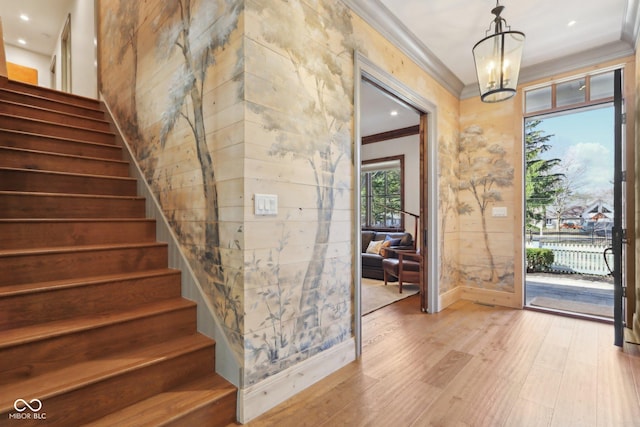 interior space featuring a notable chandelier, light wood-style floors, ornamental molding, and stairs