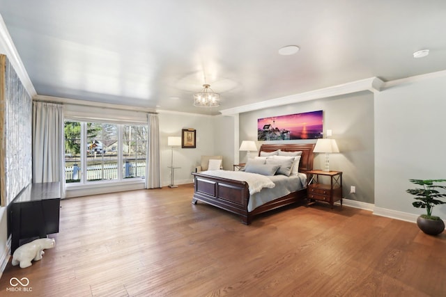 bedroom featuring baseboards, a notable chandelier, wood finished floors, and crown molding