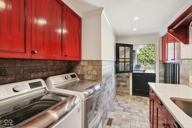 washroom featuring separate washer and dryer, cabinet space, tile walls, and ornamental molding