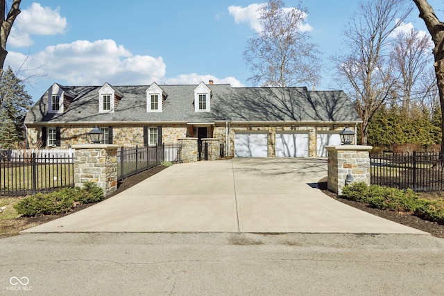 view of front of home with concrete driveway, an attached garage, stone siding, and a fenced front yard