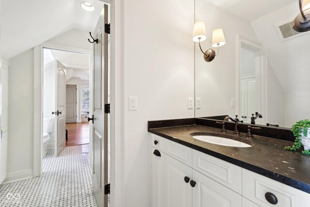 bathroom with vanity, baseboards, visible vents, lofted ceiling, and toilet