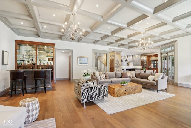 living area with beamed ceiling, a notable chandelier, wood finished floors, and indoor bar