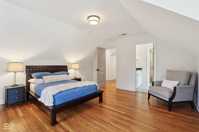 bedroom featuring visible vents, lofted ceiling, baseboards, and hardwood / wood-style flooring