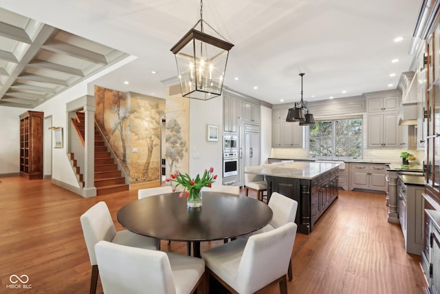 dining room featuring beam ceiling, coffered ceiling, wood finished floors, recessed lighting, and stairs