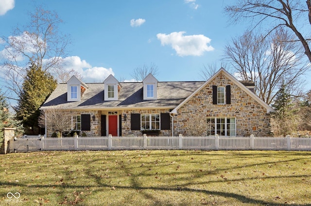 cape cod house featuring a front yard, stone siding, and a fenced front yard