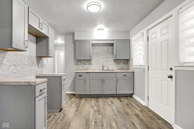 kitchen with light hardwood / wood-style flooring, sink, gray cabinets, and tasteful backsplash