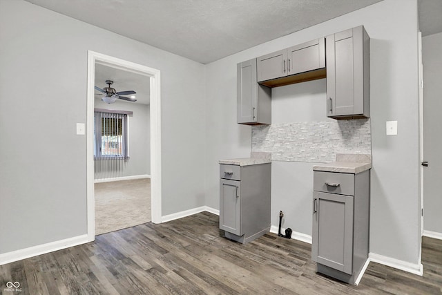 kitchen featuring gray cabinetry, backsplash, dark hardwood / wood-style flooring, and ceiling fan