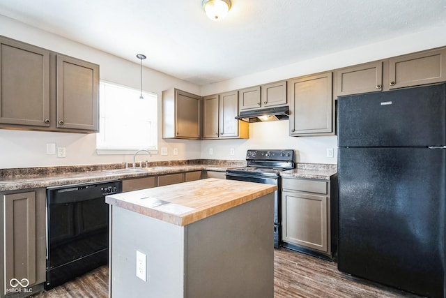 kitchen featuring a kitchen island, butcher block countertops, decorative light fixtures, sink, and black appliances