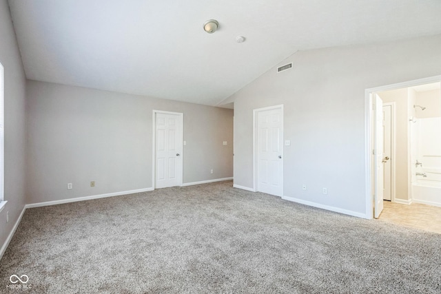 spare room featuring lofted ceiling and carpet flooring