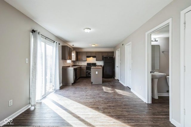 kitchen with sink, dark wood-type flooring, black fridge, and a kitchen island