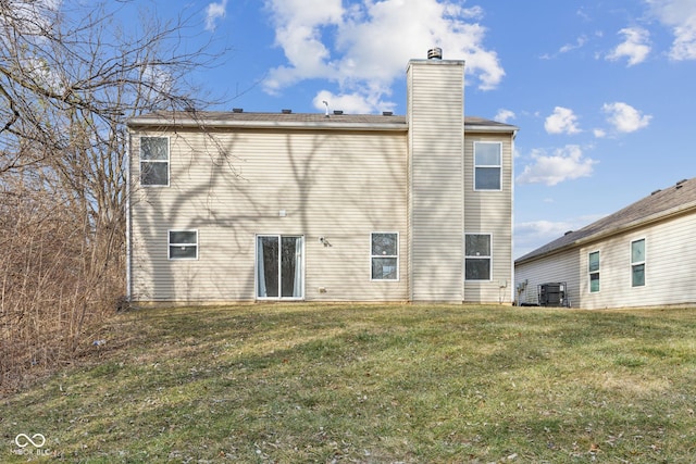 rear view of property featuring a lawn and central air condition unit