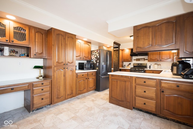 kitchen with crown molding, built in desk, wall chimney exhaust hood, and appliances with stainless steel finishes