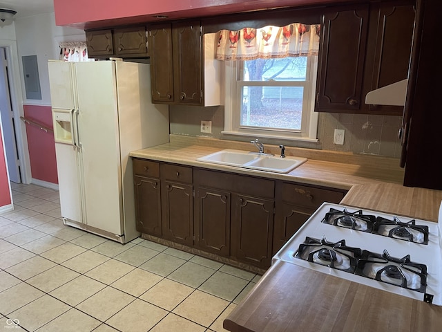 kitchen featuring dark brown cabinets, white fridge with ice dispenser, and sink