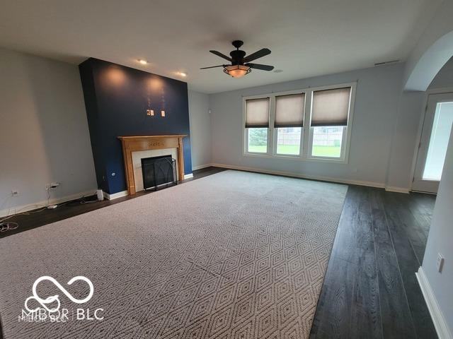 unfurnished living room featuring dark hardwood / wood-style floors and ceiling fan