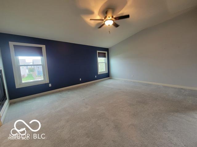 carpeted spare room with lofted ceiling and ceiling fan