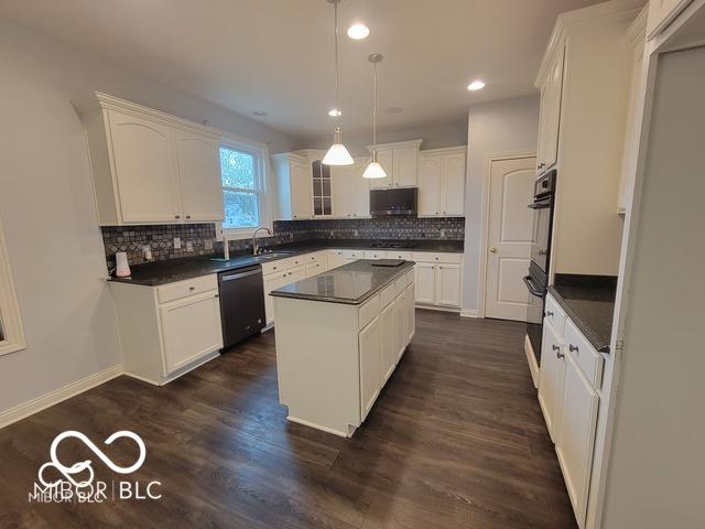 kitchen featuring sink, decorative light fixtures, stainless steel dishwasher, a kitchen island, and white cabinets